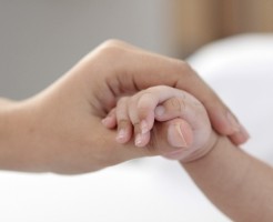 赤ちゃんの手に優しく触れる、母親の手